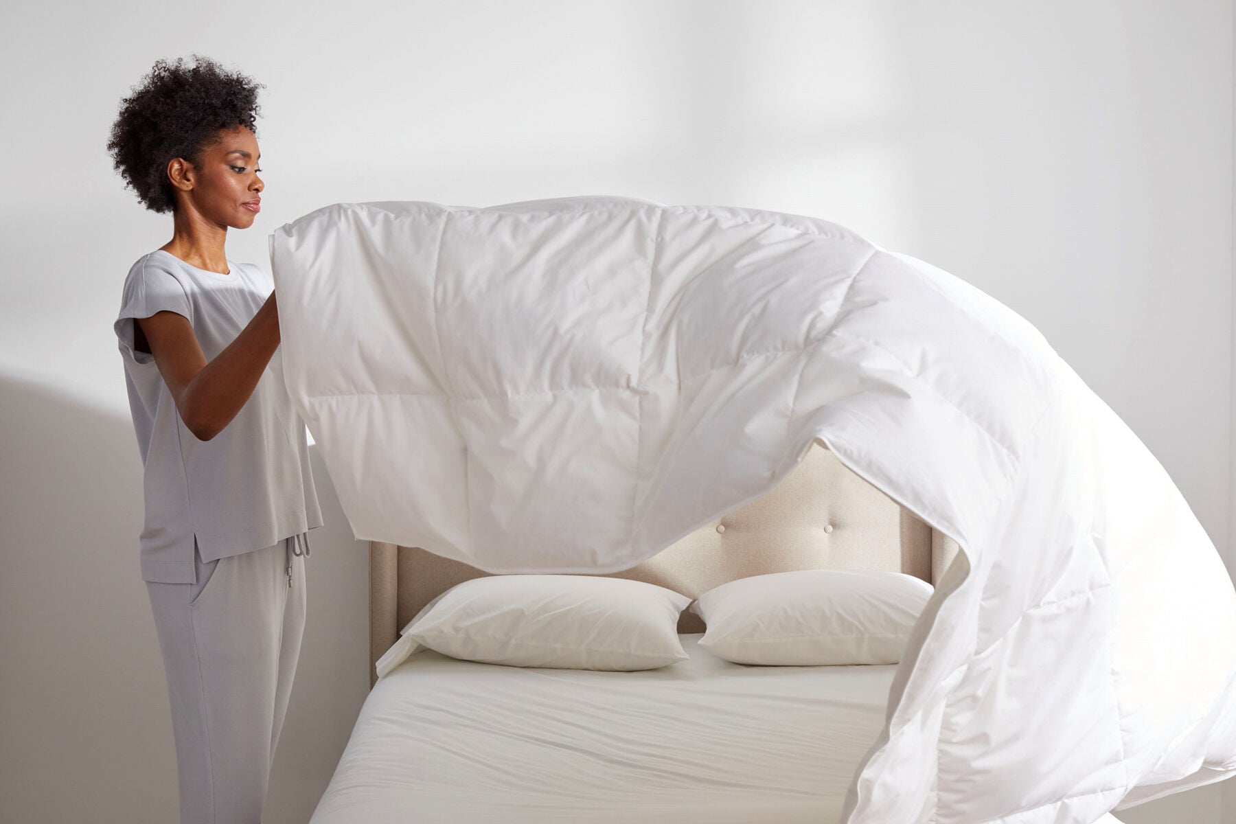 woman fluffing comforter